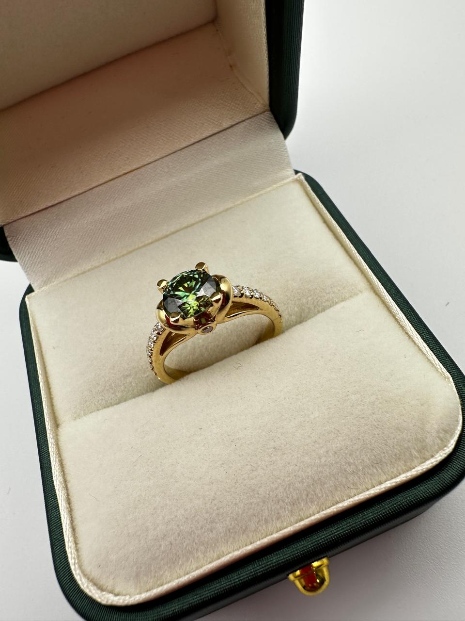Gold ring with a green gemstone in a jewelry box on a white background